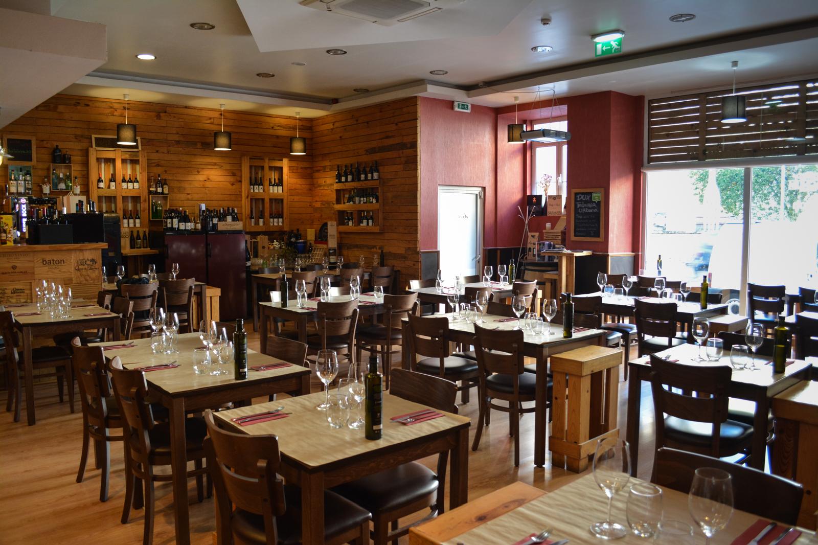 Zona interior do Dux Taberna Urbana com prateleiras de vinho e mesas postas
