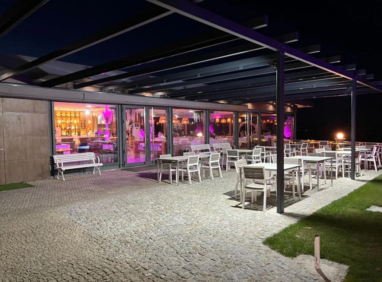 Esplanada coberta do Paraíso Douro à noite com iluminação rosa vista do jardim
