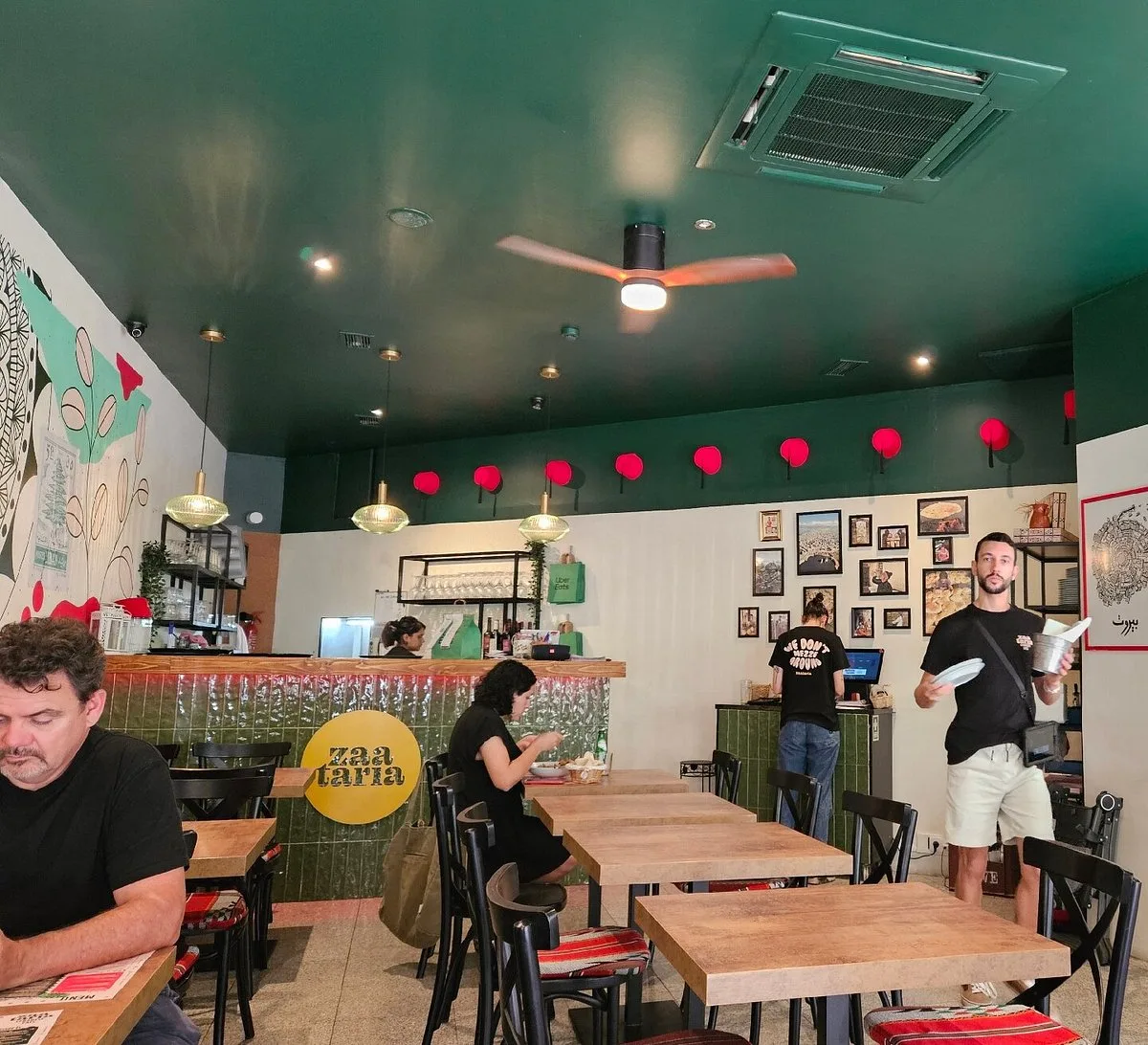 Interior do restaurante Zaataria em Lisboa com pinturas na parede e luz ambiente