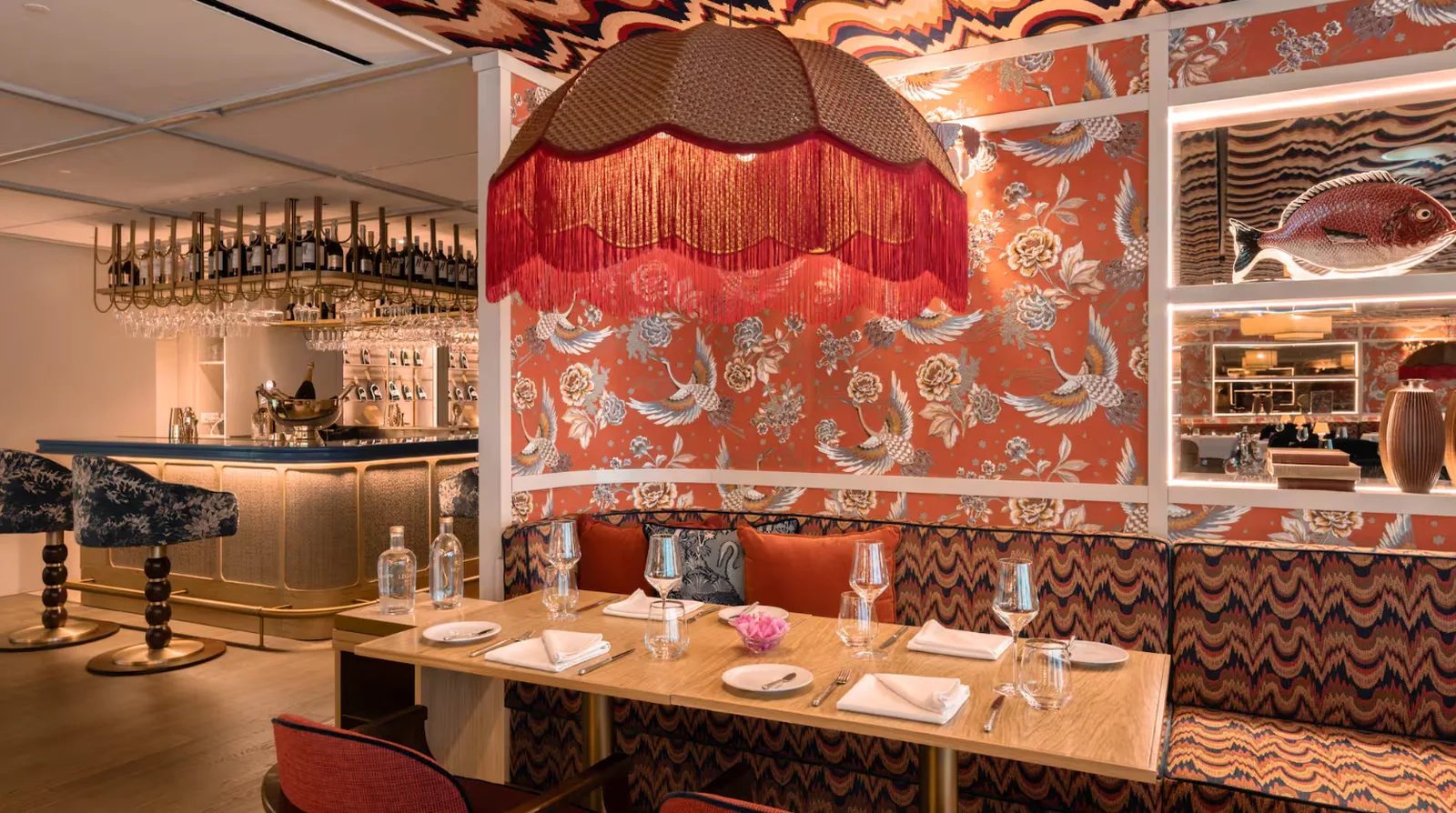 Sala do restaurante Ardea em Cascais com papel de parede floral, bancos corridos e bar dourado